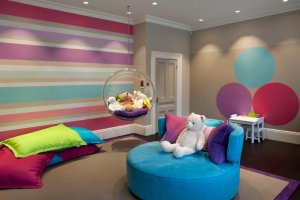 a-cozy-colorful-stripe-wallpaper-idea-for-baby-nursery-room-with-blue-comfort-sofa-and-colorful-circle-wall-decors-also-transparant-round-toys-swing-801x534